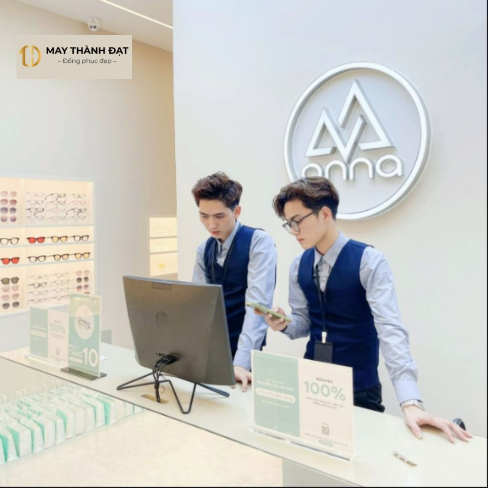 Nhân viên nam showroom Kính mắt Anna mặc đồng phục gile xanh đen phối sơ mi màu ghi sáng